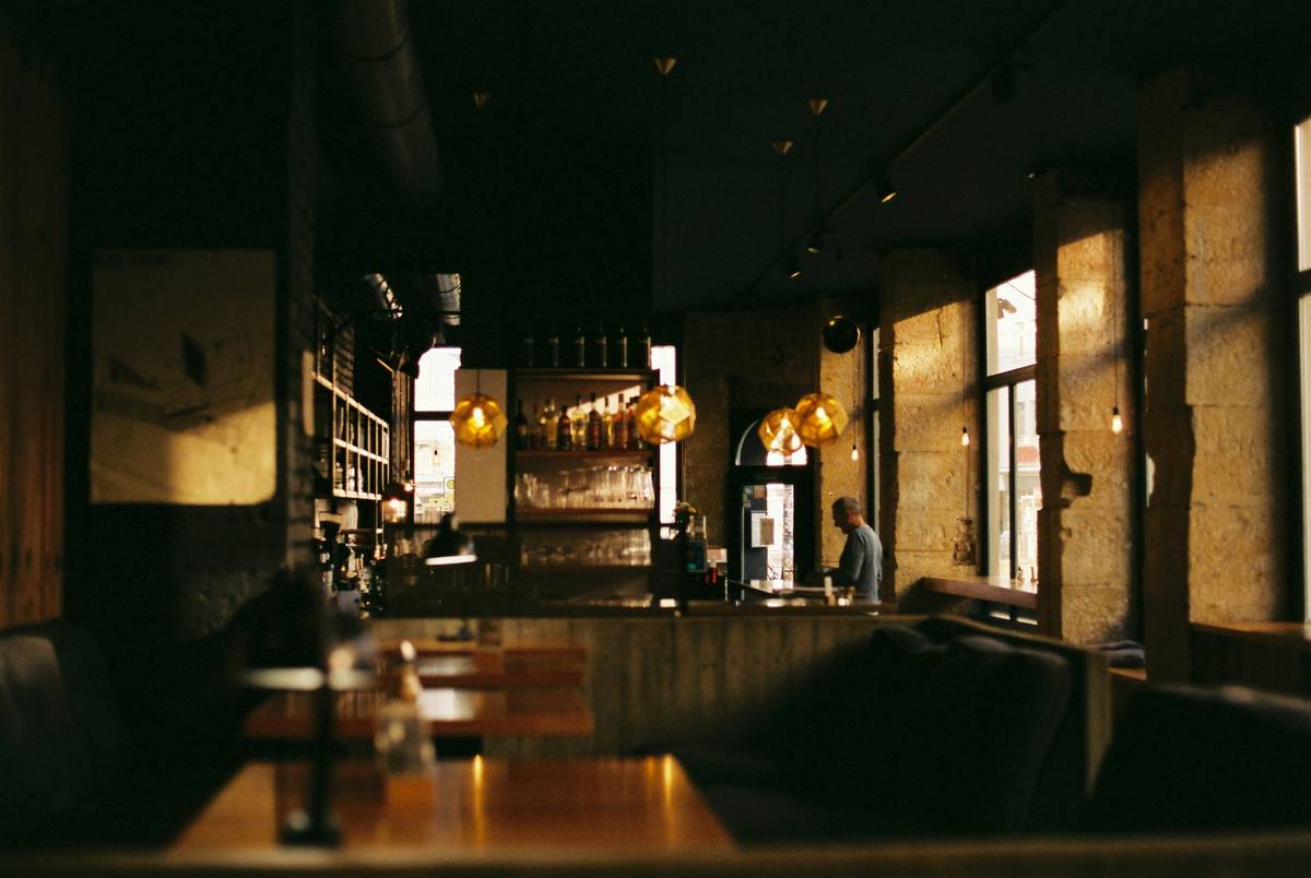 restaurant mood lighting with warm pendant fixtures over wooden tables and soft wall sconces